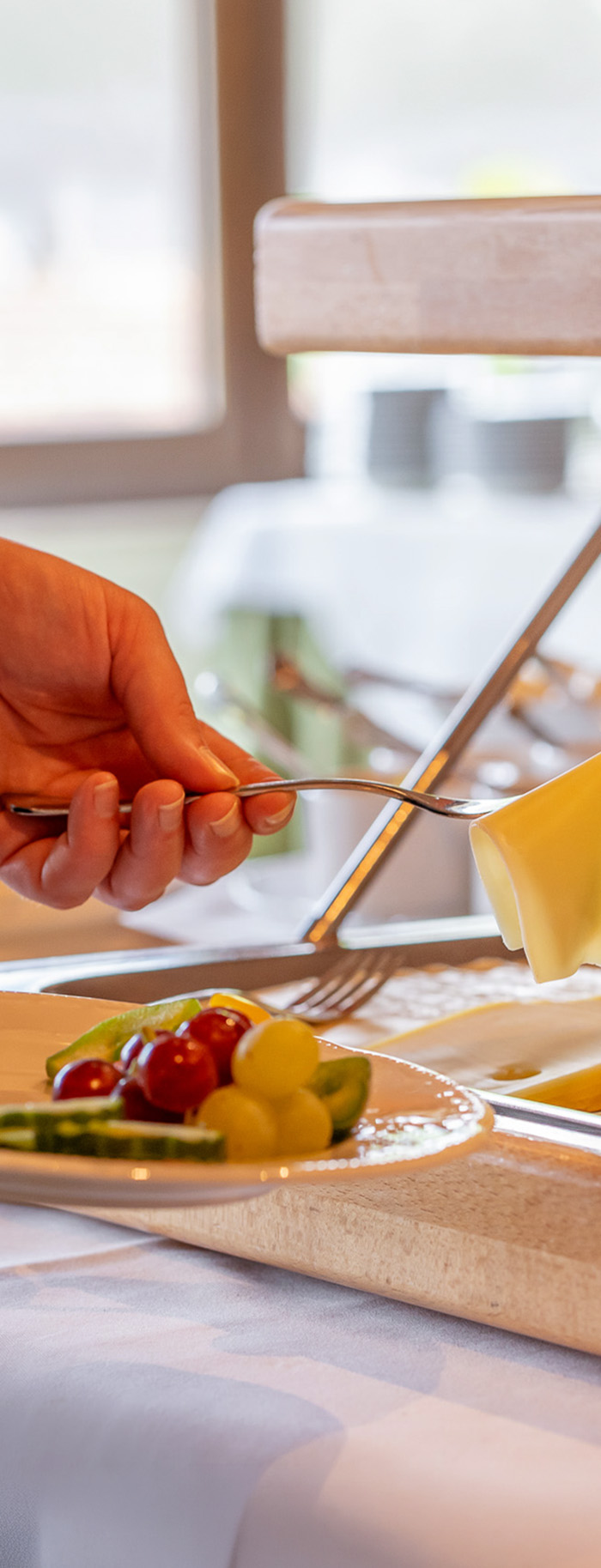 Hand die am Frühstücksbuffet Käse aufhebt