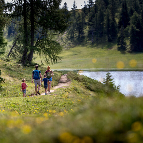 Zwei Erwachsene und ein Kind wandern an einem See entlang