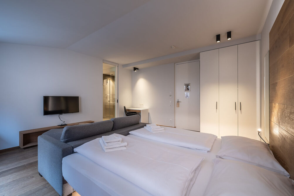 Doppeltbett mit einem Sofa davor in einem Hotelzimmer