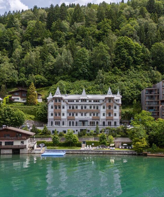 Seehotel Bellevue mit dem See im Vordergrund und dem Wald im Hintergrund