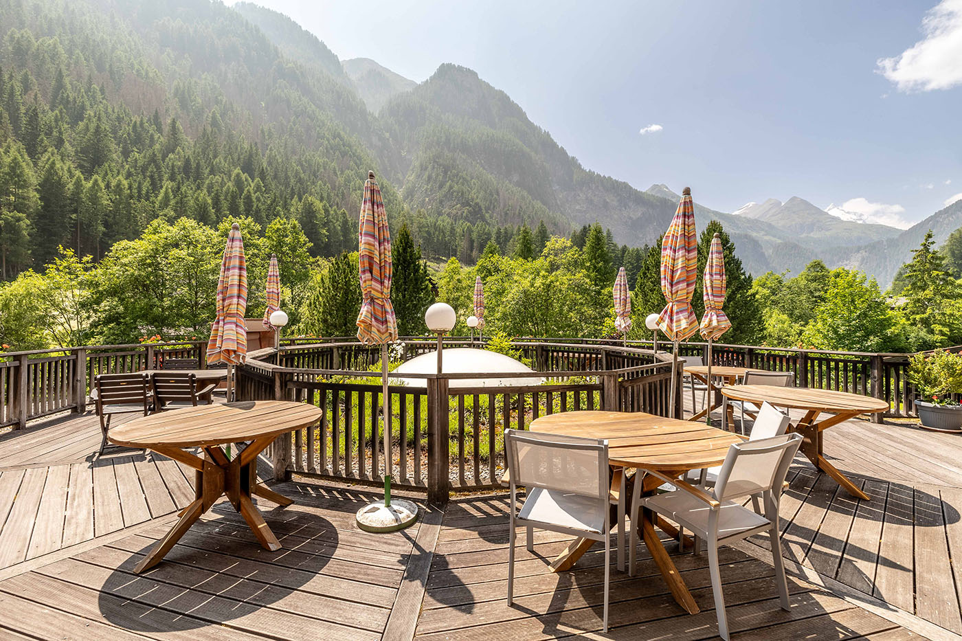 Terasse mit Stühlen und Tischen vor Bergen im Hintergrund