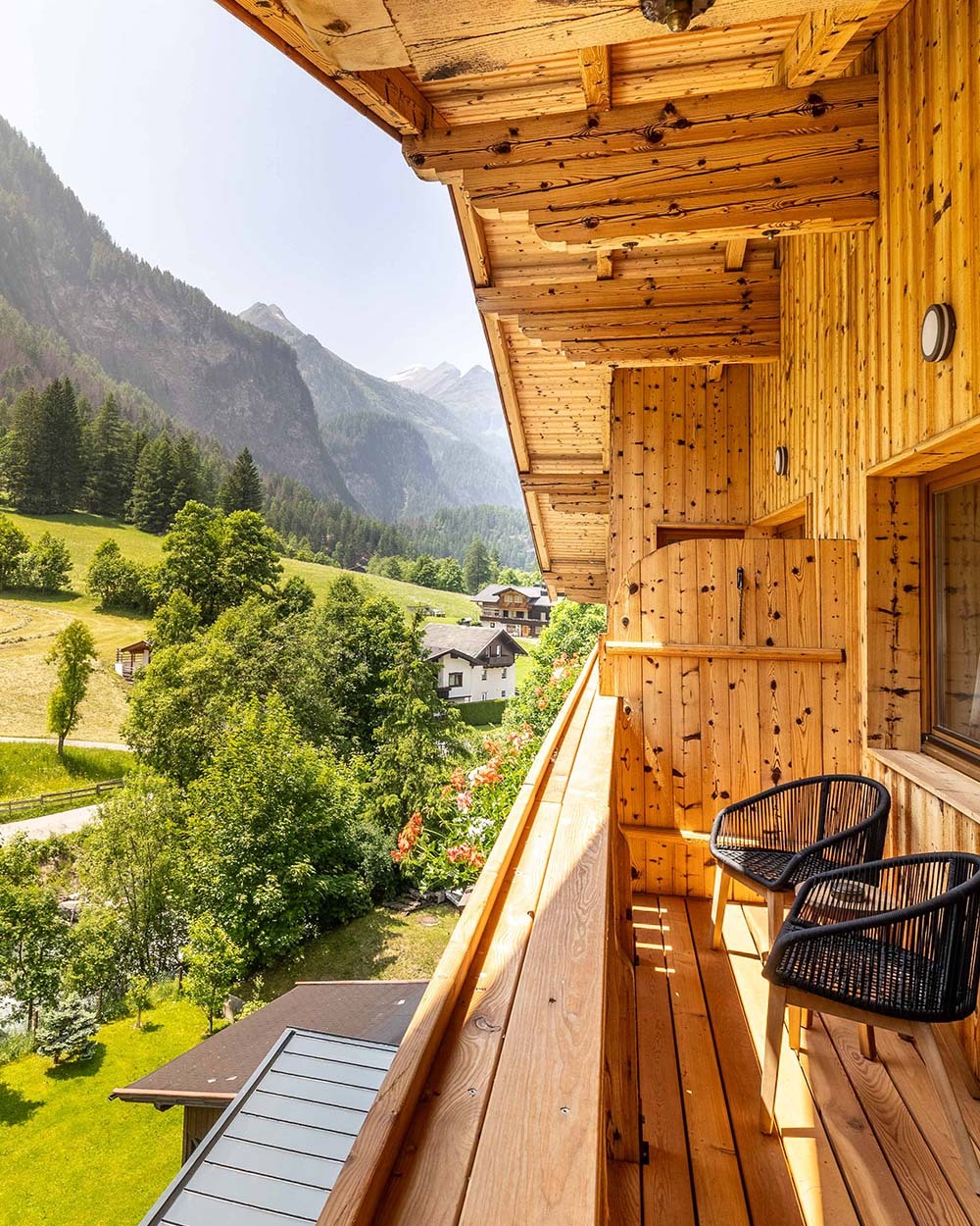 balkon mit zwei Stühlen und Aussicht auf Wiesen und Berge