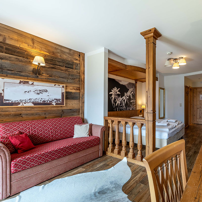 Innenansicht eines Zimmers mit rotem sofa und Doppelbett