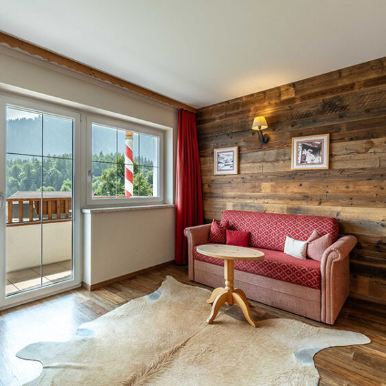 Rotes Sofa mit kleinem Holztisch in einem Zimmer mit Balkon